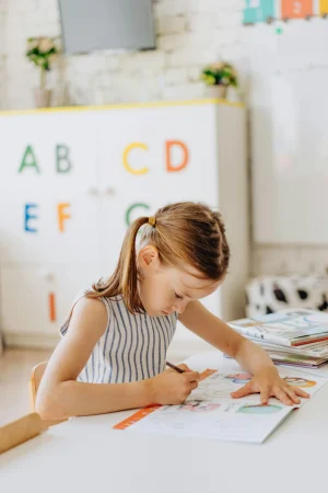 A young girl focused on coloring a book in a primary classroom setting, enhancing learning.